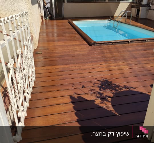 בריכת שחייה על דק עץ עם מעקה מתכת לבן